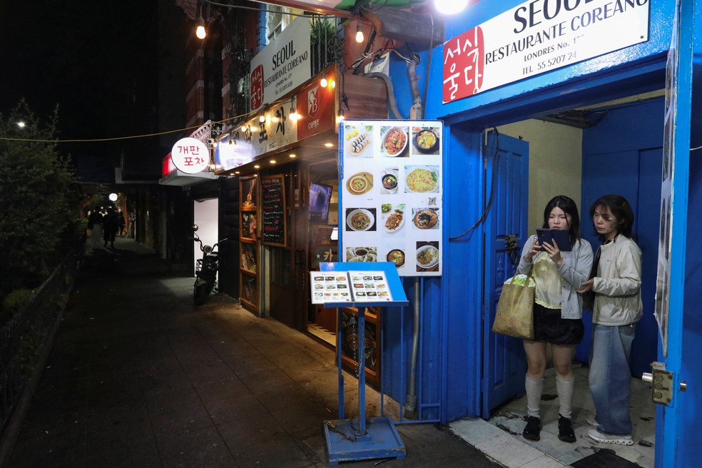 Sul- coreanos aguardam na entrada de um restaurante em Seul, no bairro de Little Seoul. A relação entre a Coreia e o México é uma das histórias de amor geocultural mais incomuns do mundo, com a influência coreana ganhando terreno apesar da distância, do idioma e da diferença de fuso horário de 15 horas. A foto foi tirada na Cidade do México, México, em 17 de junho de 2026 — Foto: REUTERS/Paola Garcia